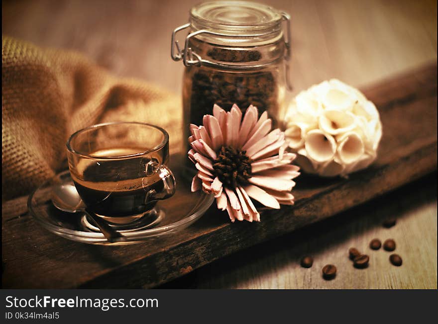 Lovely composition with a cup of coffee and coffee beans and a flower on a wooden table