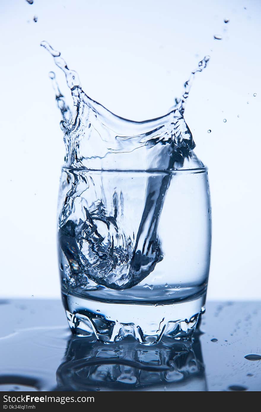 A fresh splash of mineral water in a glass of ice cube, a good gradient background. A fresh splash of mineral water in a glass of ice cube, a good gradient background.