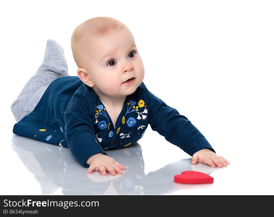 A cute, very little girl is lying on the floor on a white backgr