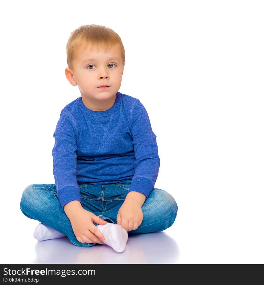 Cute little boy is sitting on the floor on a white background. The concept of a happy childhood, the harmonious development of the child in the family. Isolated.