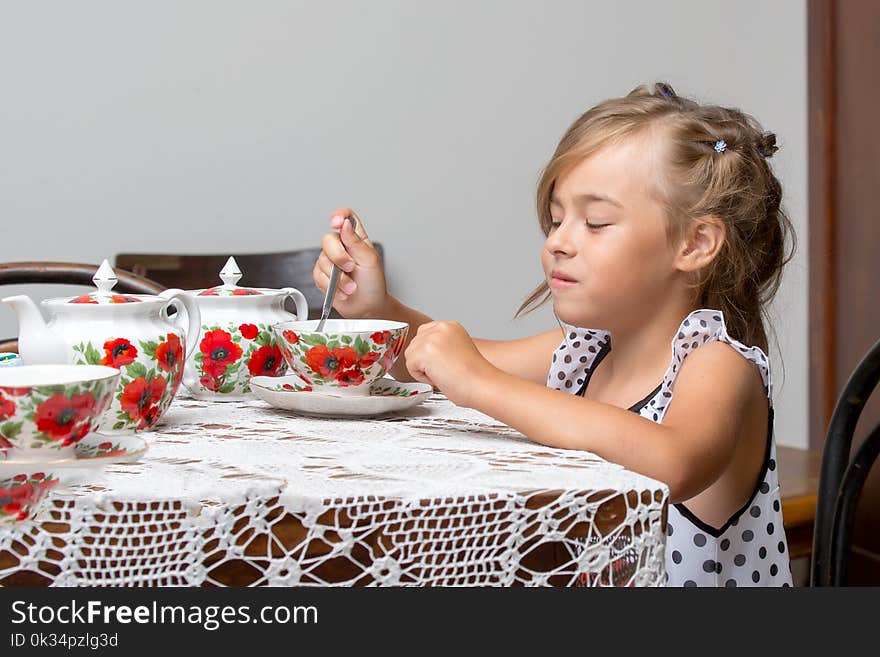 A little girl is drinking tea at the table. Stylized as a room of the fifties of last century. Retro style.