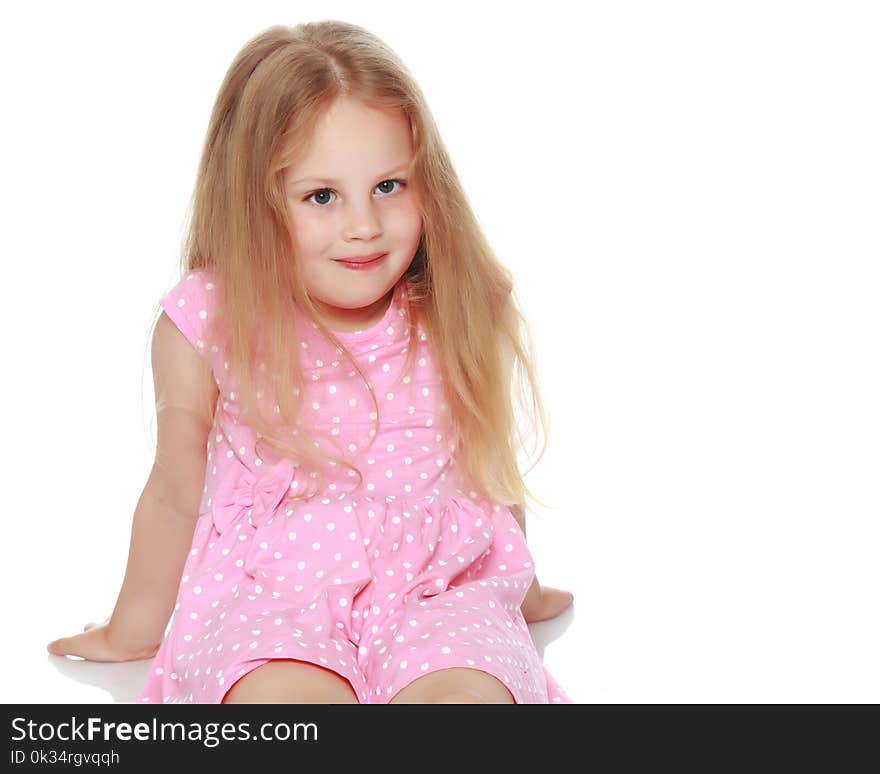 Little girl is sitting on the floor. The concept of a happy childhood. Isolated on white background.