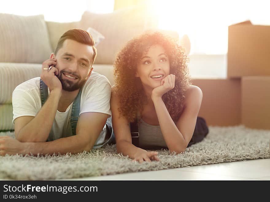 Young couple lying on the rug on the background of a new apartme