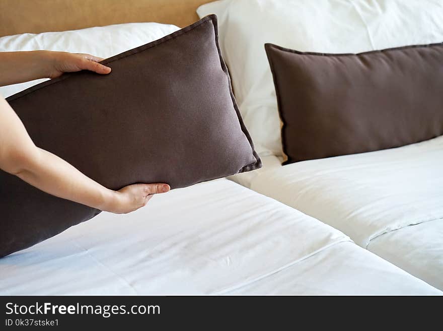 Maid making bed in hotel room.