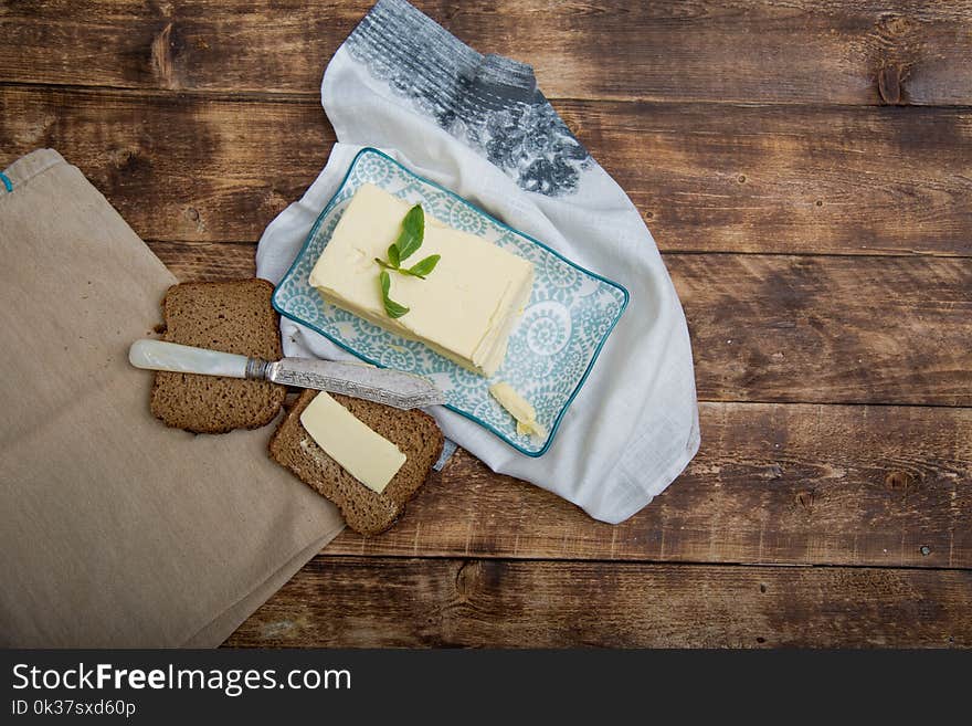 A piece of bread with butter on wooden background and napkin