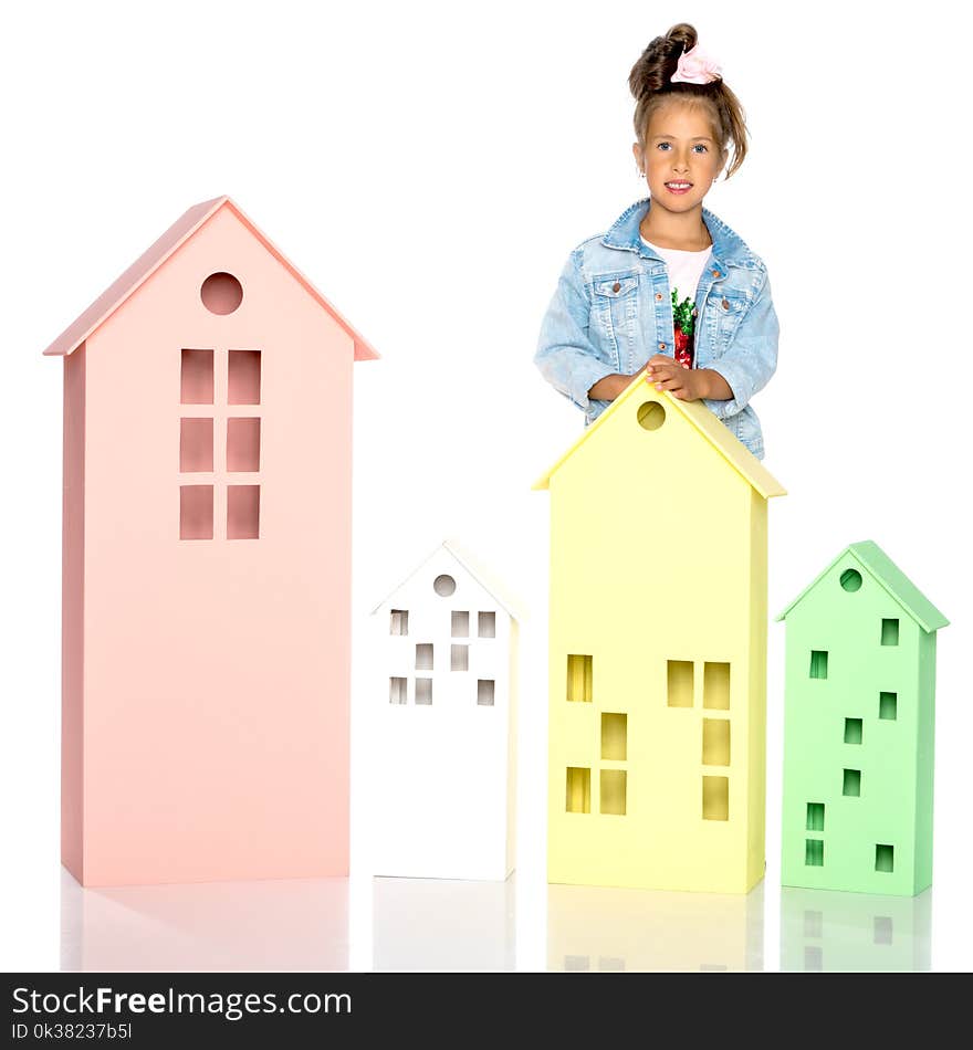 A cute little girl is playing with wooden houses. The concept of family happiness, play, creative development of the child.