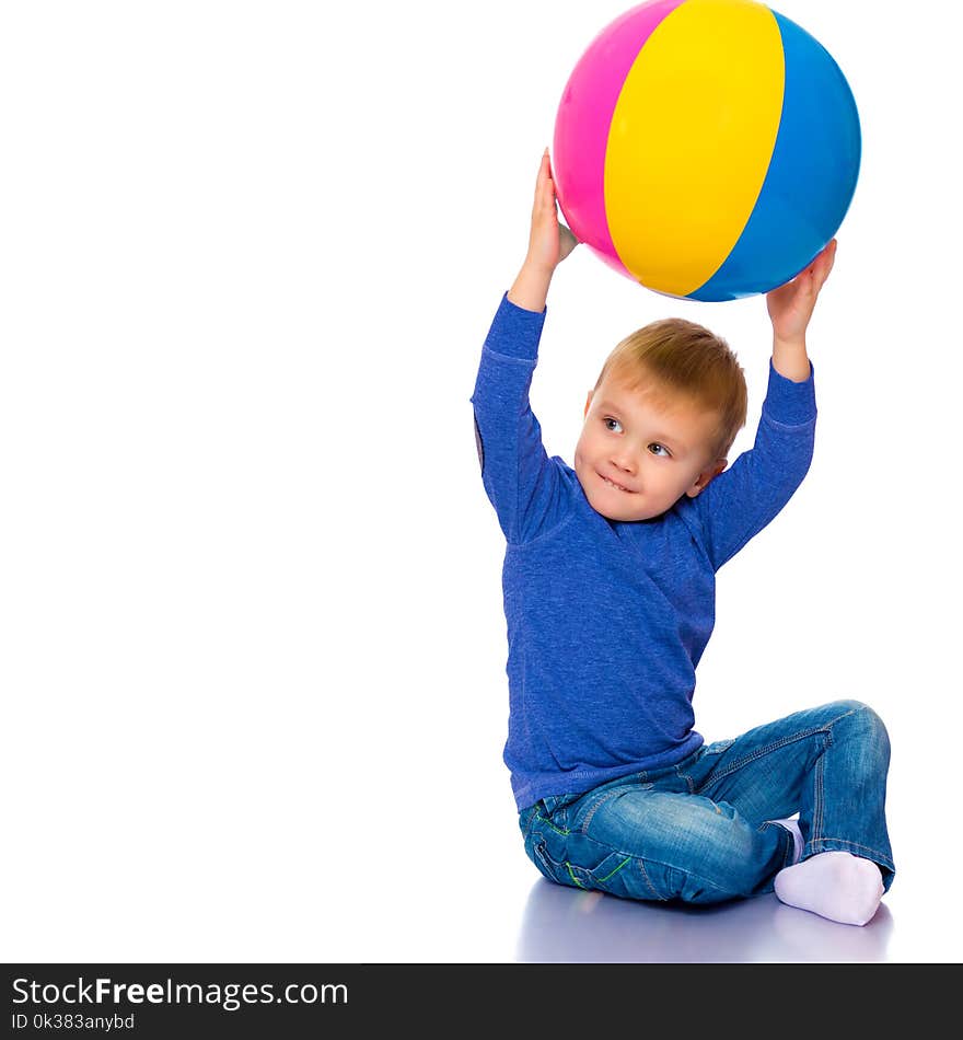 A cheerful little boy is playing with a ball in the studio on a white background. The concept of a happy childhood, game and sport. Isolated. A cheerful little boy is playing with a ball in the studio on a white background. The concept of a happy childhood, game and sport. Isolated.