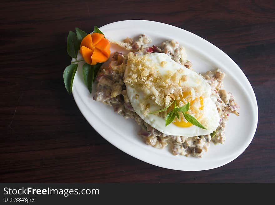 Serving of Marinated Meat With Sunny Side-up Egg and Slice of Carrot in Oval White Ceramic Plate