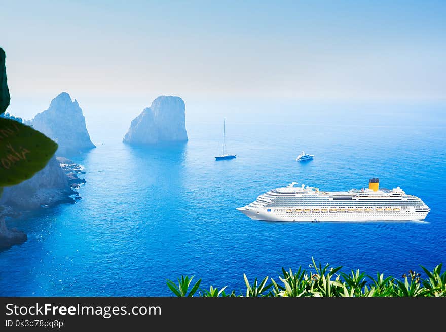 Famous Faraglioni cliffs and Tyrrhenian Sea blue water with criuse ship, Capri island, Italy