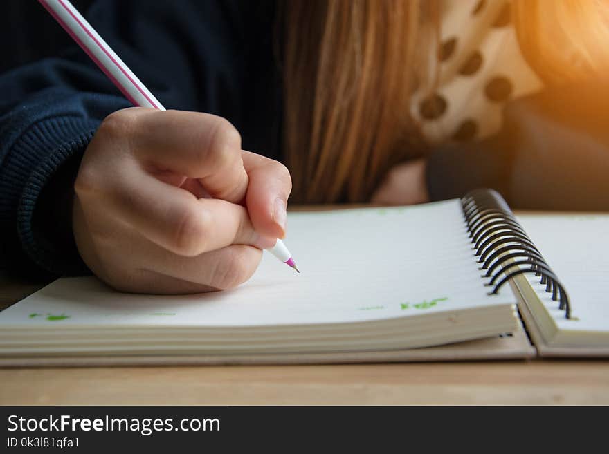 Female hand writing in notebook on the table.