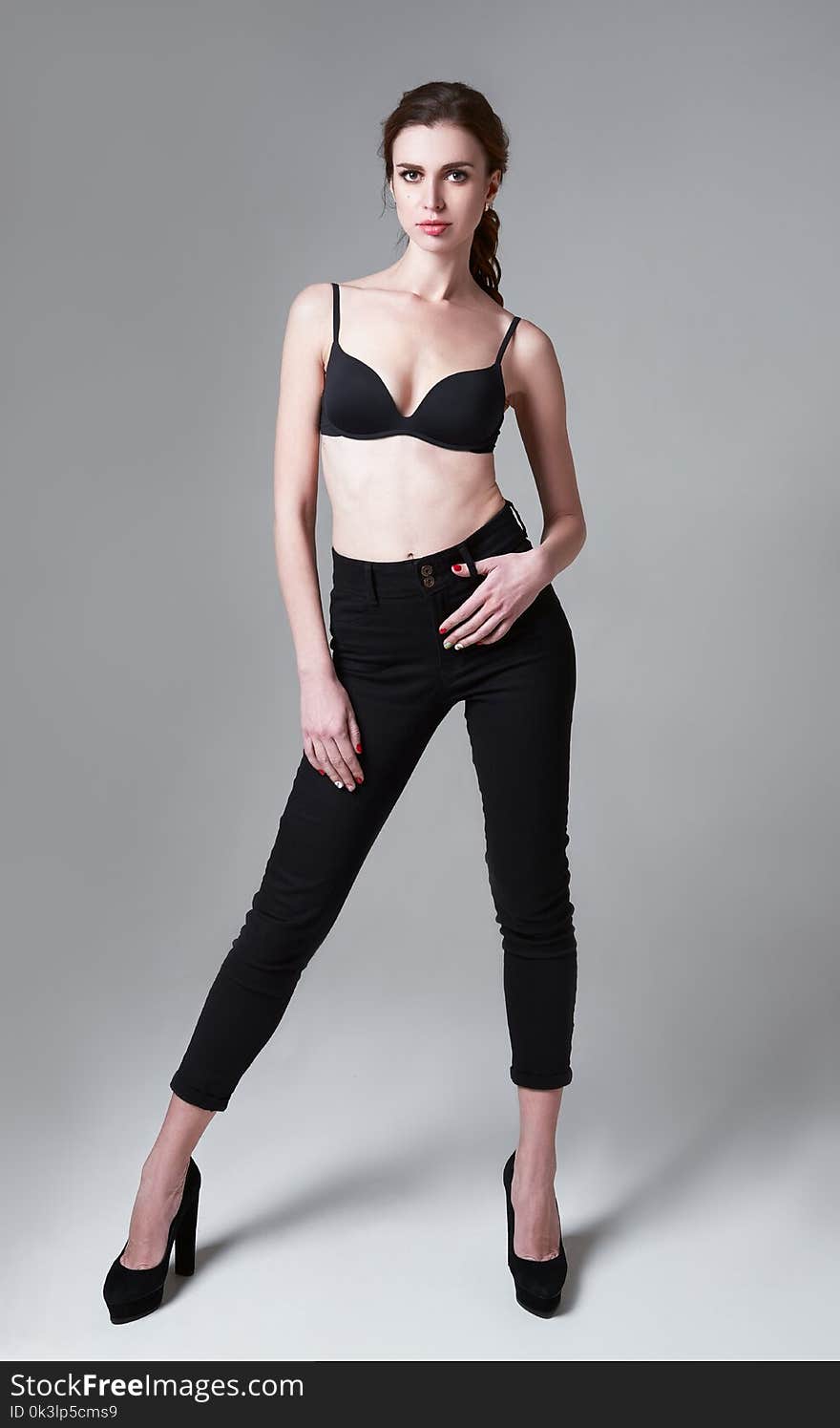 Studio fashion shot: portrait of attractive young woman in pants and bra. Full length