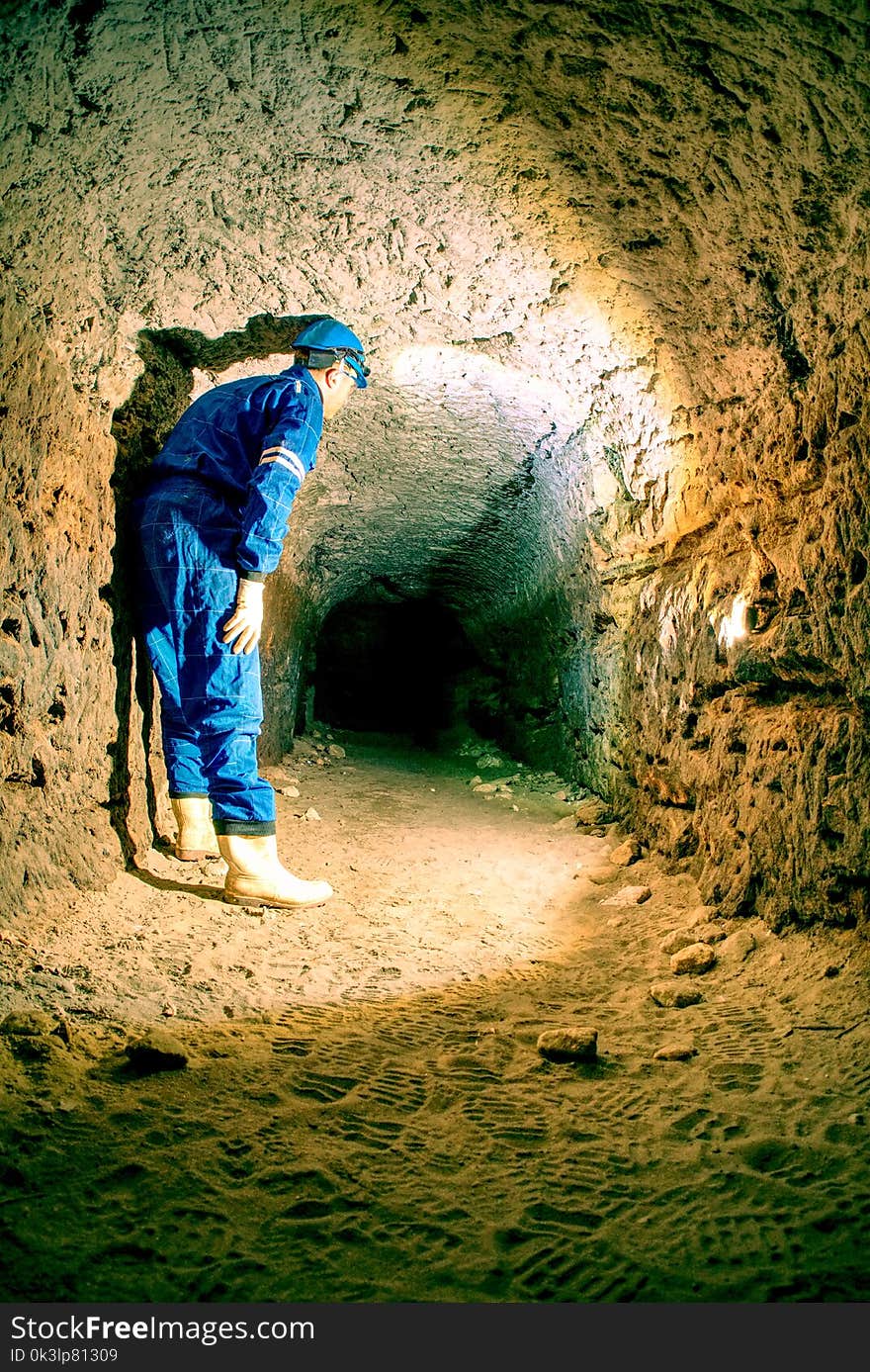 Workerman with helmet and protective suit using glowes and head lamp. Man do job in old mine ventilation shaft. Underground worker. Workerman with helmet and protective suit using glowes and head lamp. Man do job in old mine ventilation shaft. Underground worker.