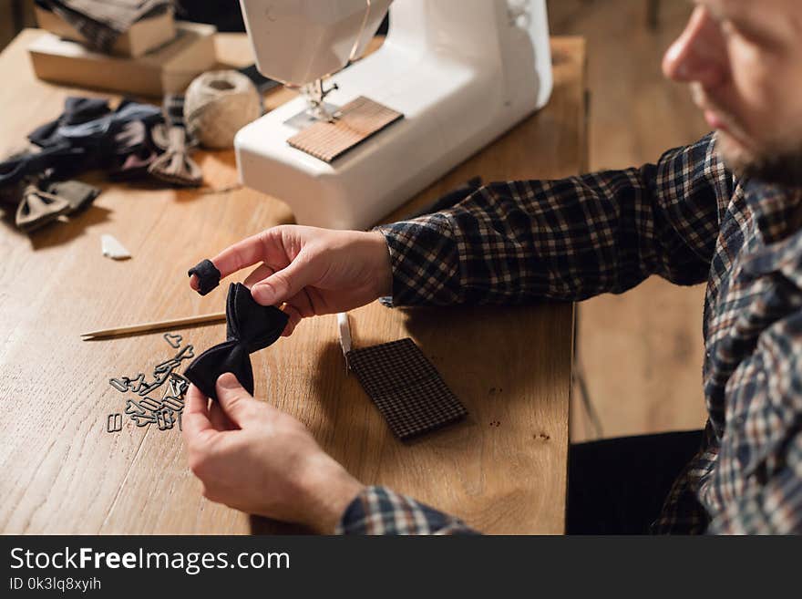 Good looking young man working as a tailor and using a sewing machine in a textile studio. makes bow ties butterflies. Good looking young man working as a tailor and using a sewing machine in a textile studio. makes bow ties butterflies