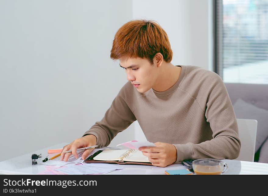 Young attractive Young Asian man at home sitting on sofa with ca