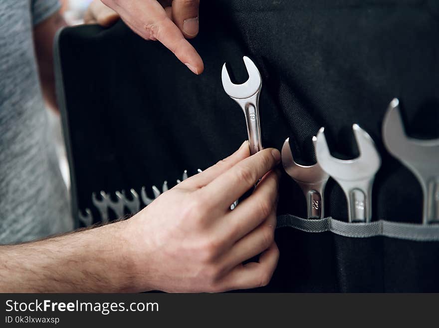 Salesman in checkered shirt is showing bearded client set of wrenches in power tools store. Salesman in checkered shirt is showing bearded client set of wrenches in power tools store.