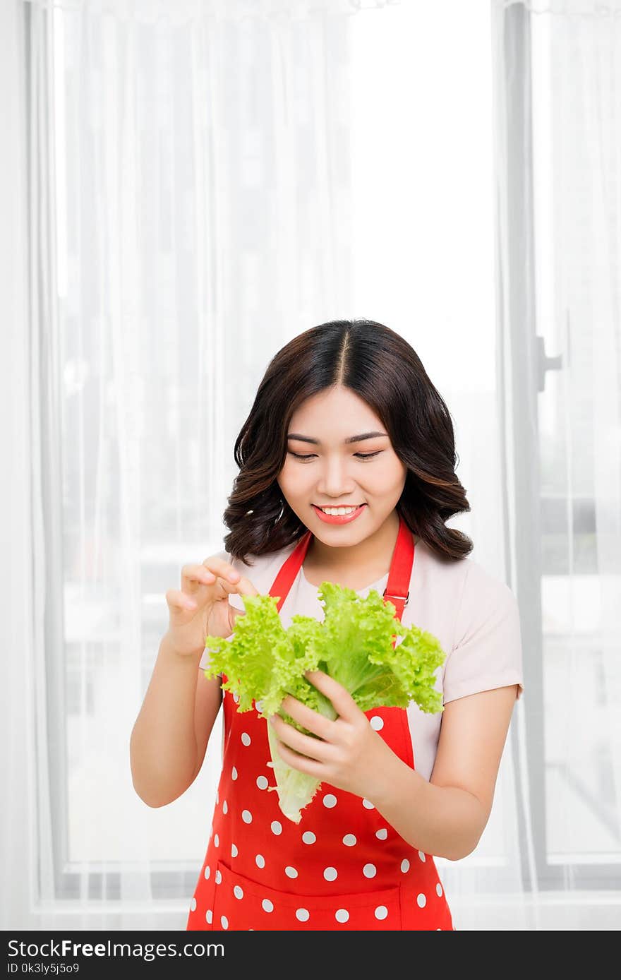 Picture of happy woman with lettuce in kitchen