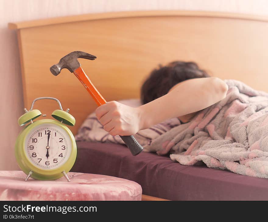 Beating the alarm clock with hammer. concept of sleep