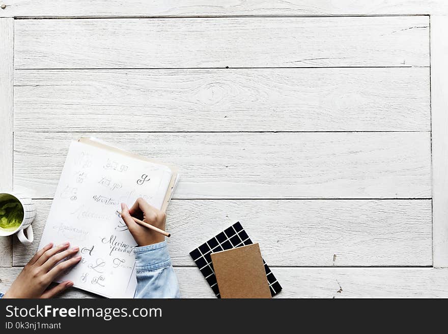 Person Holding Pencil While Writing on White Paper