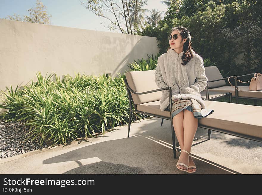 Woman Wearing Hoodie Sitting on Lounge Chair