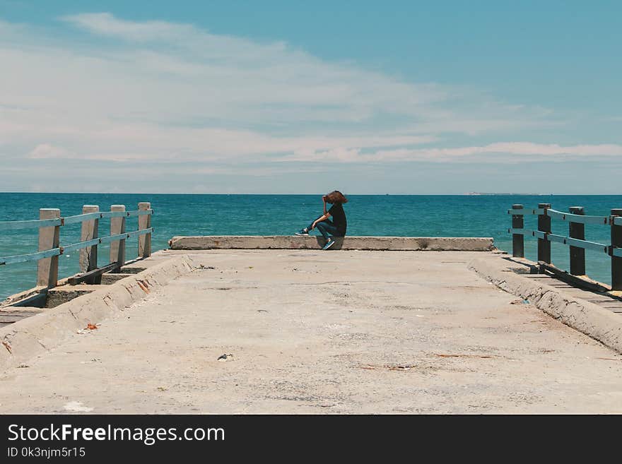 Person Sitting on the Edge of the Beach Dock