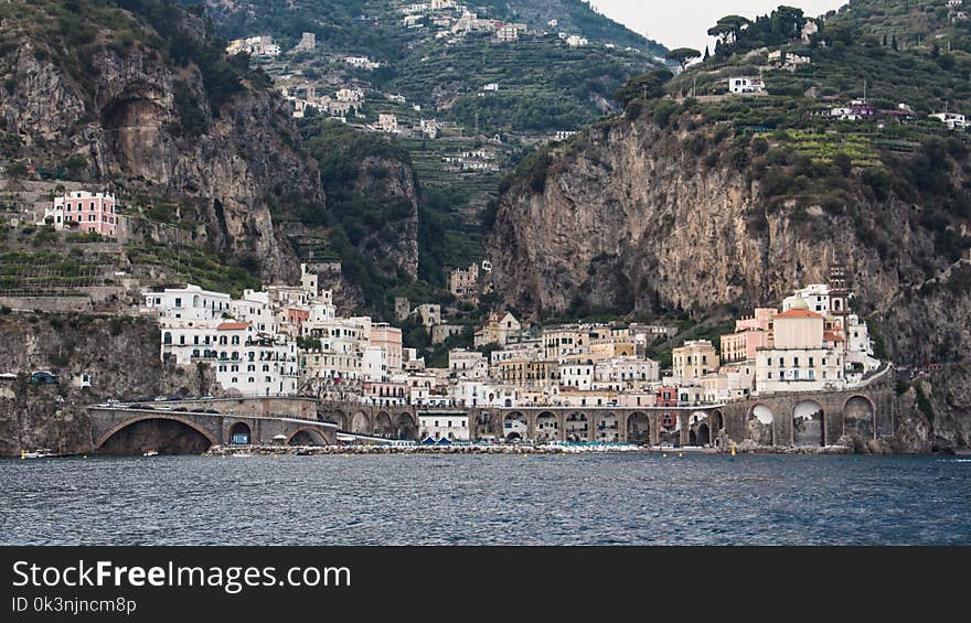 White Buildings Beside Mountain and Body of Water