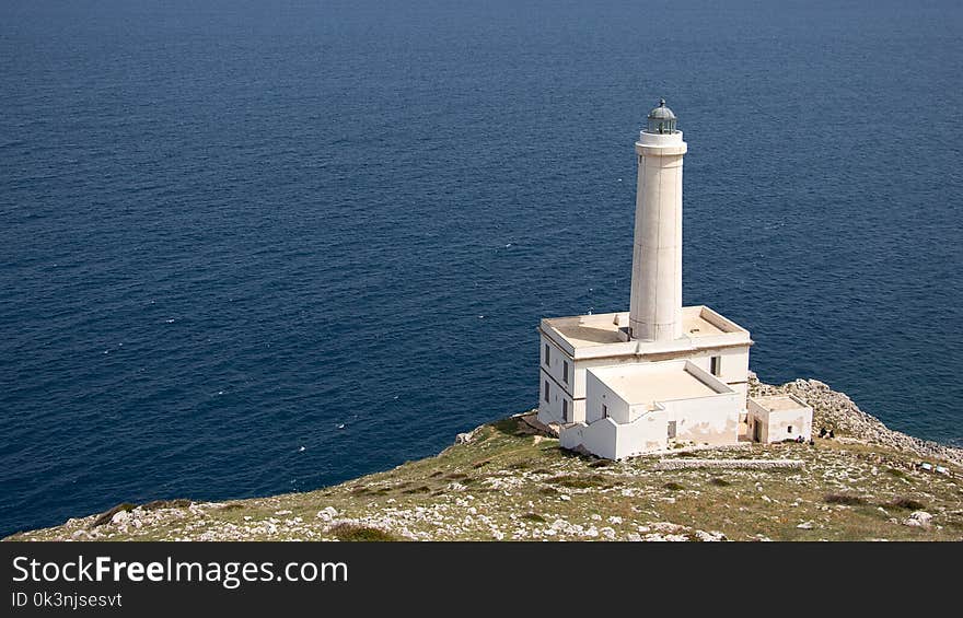 White Lighthouse on Cliff Near Body of Water