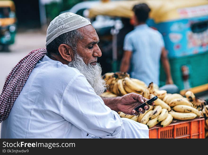 Man in White Thobe Coat Holding Mobile Phone