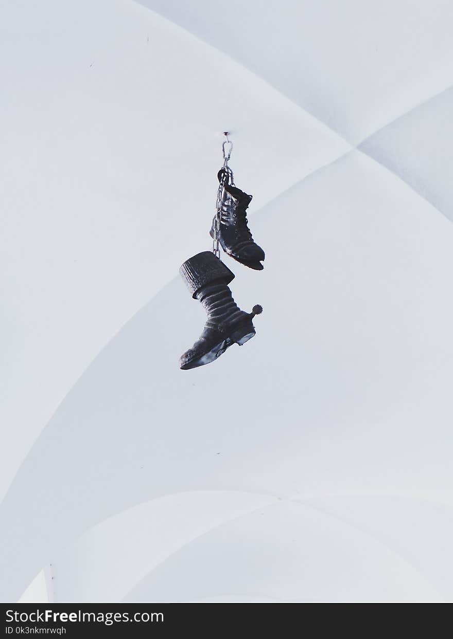 Pair of Black Boots Hanging on White Wall