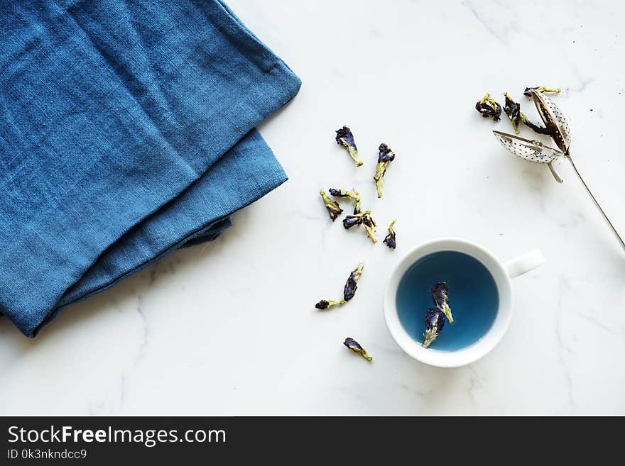 White Ceramic Teacup Near Blue Textile