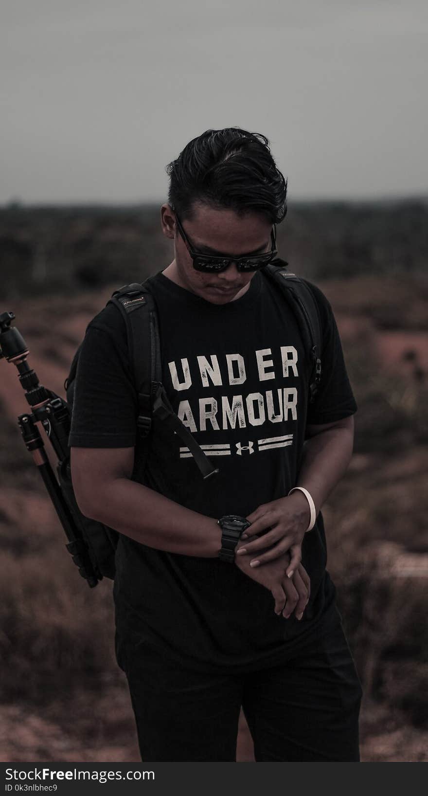 Man Wearing Black and White Under Armour Shirt and Holding His Watch