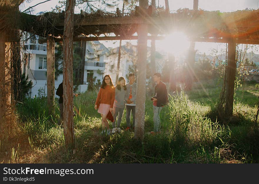 Four People Standing on Green Grass Near White Concrete House