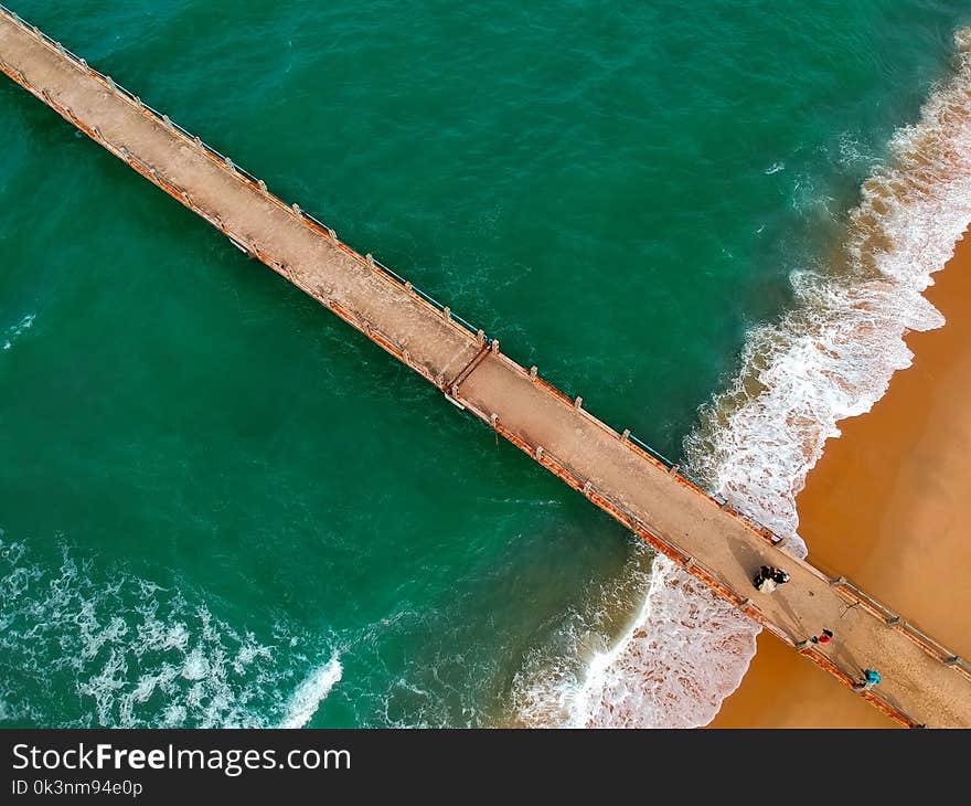 Aerial Photography of Brown Boardwalk Near Green Water on Beach