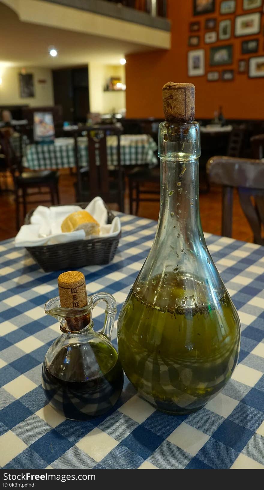 A italian restaurant traditional scene with some old glass bottles in the middle of the table containing oil to be added to the food, bread basket in the back. A italian restaurant traditional scene with some old glass bottles in the middle of the table containing oil to be added to the food, bread basket in the back