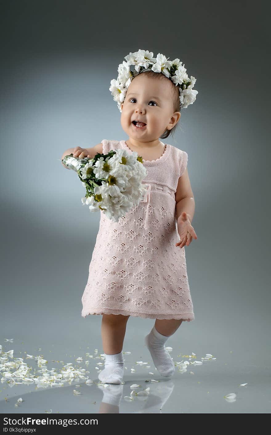 Beautiful little baby girl, with bouquet and diadem of flowers