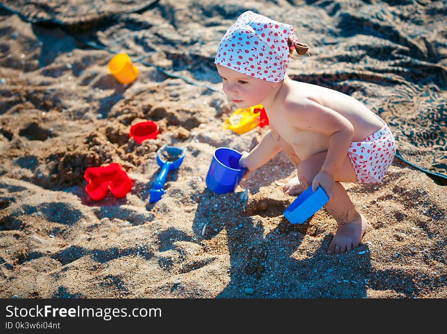 Cute little girl sitting on the beach and playing with plastic toys. Cute little girl sitting on the beach and playing with plastic toys.