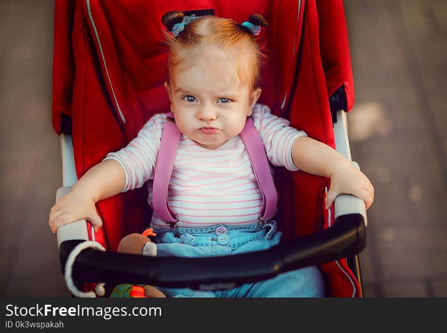 Adorable little girl sitting and riding in baby carriage on the street. Adorable little girl sitting and riding in baby carriage on the street.