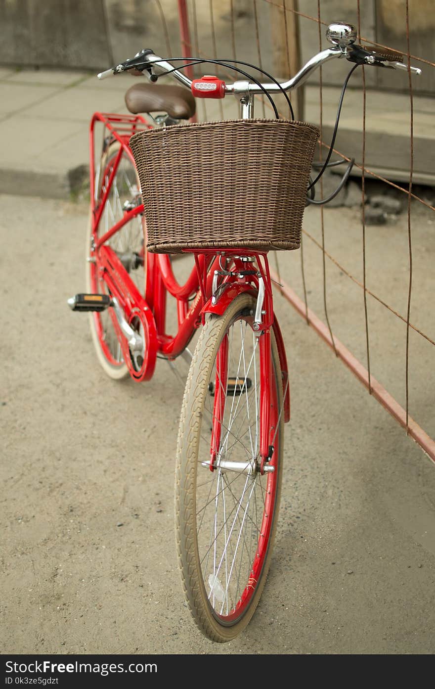 Red vintage city bicycle with brown basket on the handlebar standing outdoors. Red vintage city bicycle with brown basket on the handlebar standing outdoors