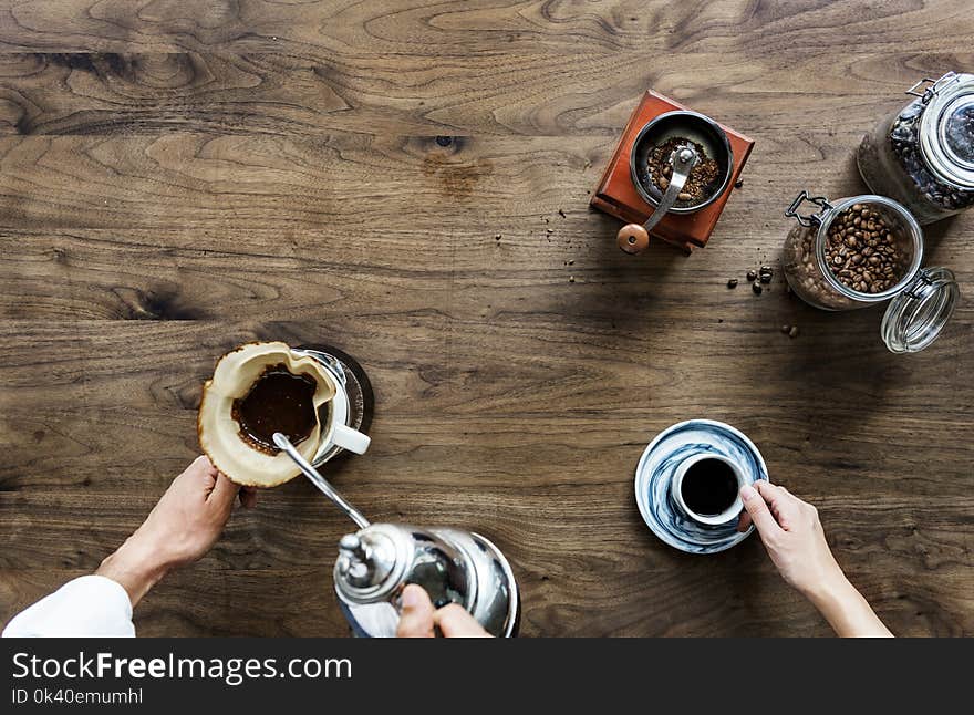 Person Making Coffee Beside Person Holding Cup of Coffee