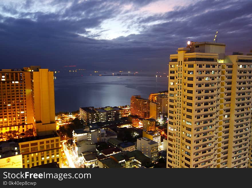 Cityscape Lighted High-rise Buildings Beside Calm Body of Water