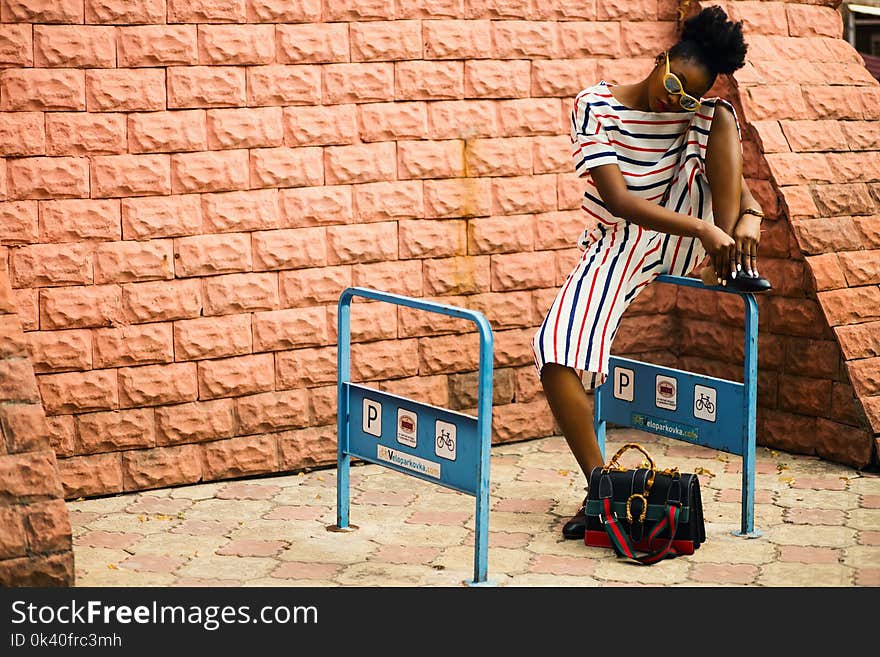 Woman With Striped Romper Sitting on Blue Metal