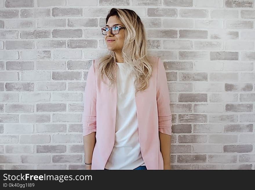 Woman in Pink Cardigan and White Shirt Leaning on the Wall