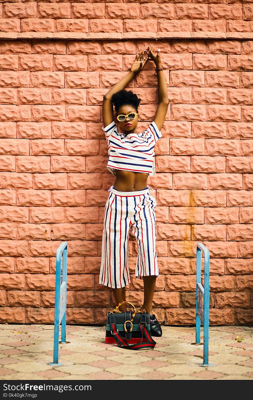 Woman in White, Blue, and Rd Shirt Leaning on Wall