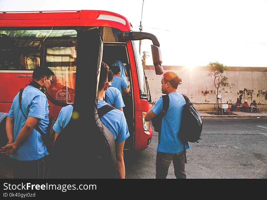 Group of Men Wearing Blue Shirts About to Enter Red Bus