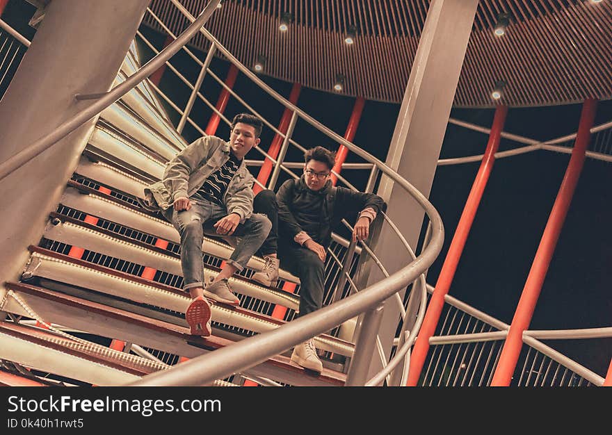 Two Men Sitting on Spiral Stairway