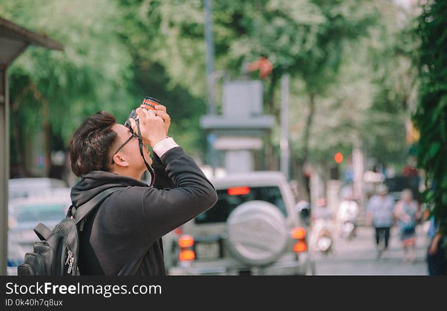 Man Wearing Black Hoodie Holding Dslr Camera Shooting on Upper Direction