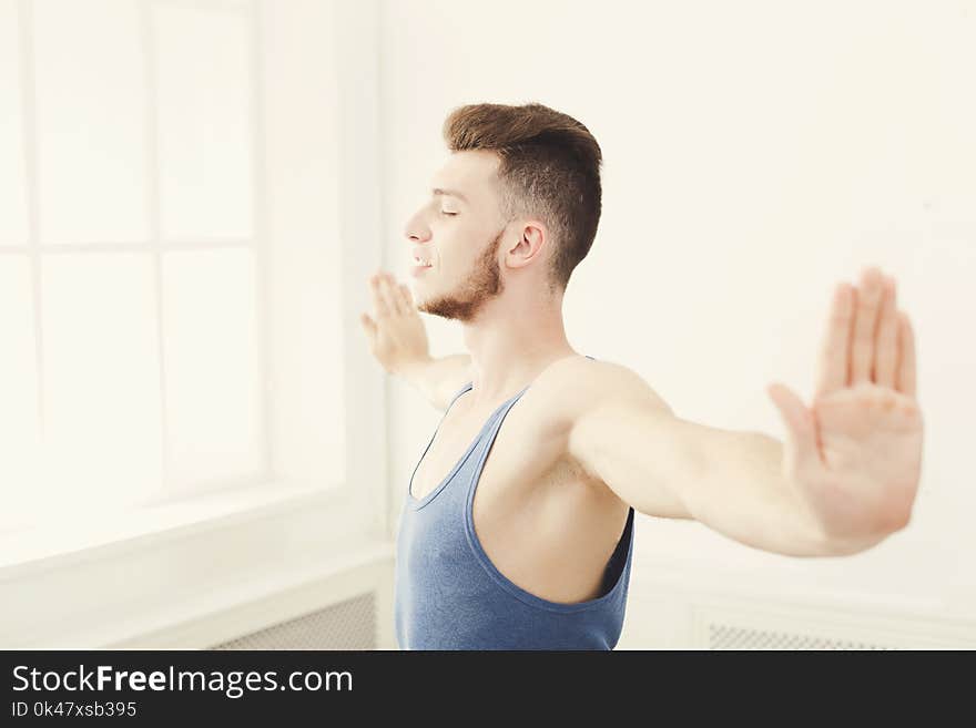 Man training yoga pose in gym at white background, copy space. Young boy makes exercise, fitness, meditation. Man training yoga pose in gym at white background, copy space. Young boy makes exercise, fitness, meditation