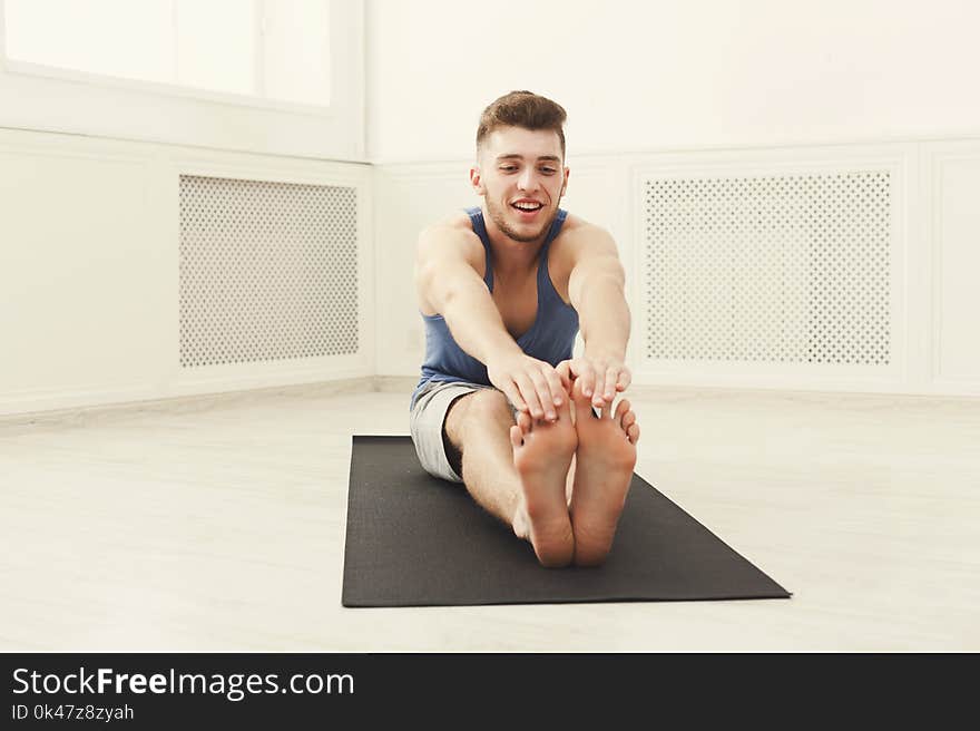 Man warmup stretching training at white background indoors, copy space. Young boy makes exercise. Man warmup stretching training at white background indoors, copy space. Young boy makes exercise.