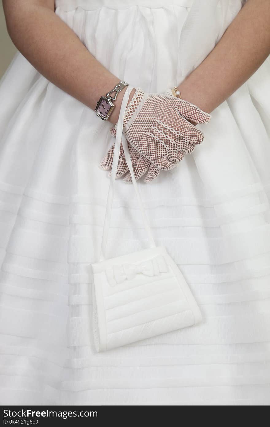 Detail of communion hands of a girl dressed in white with a coin purse in her hand