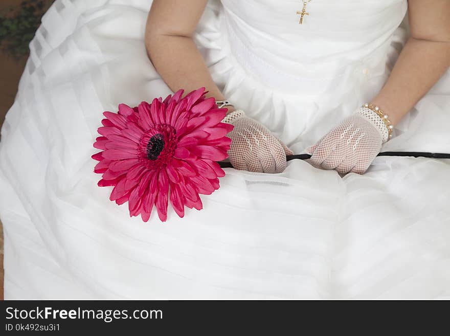 Detail of the hands of a communion girl dressed in white with a flower in her hands