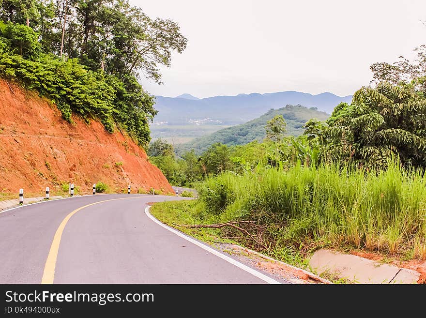 Country road down from the hill, mountain far away ahead, Thailand